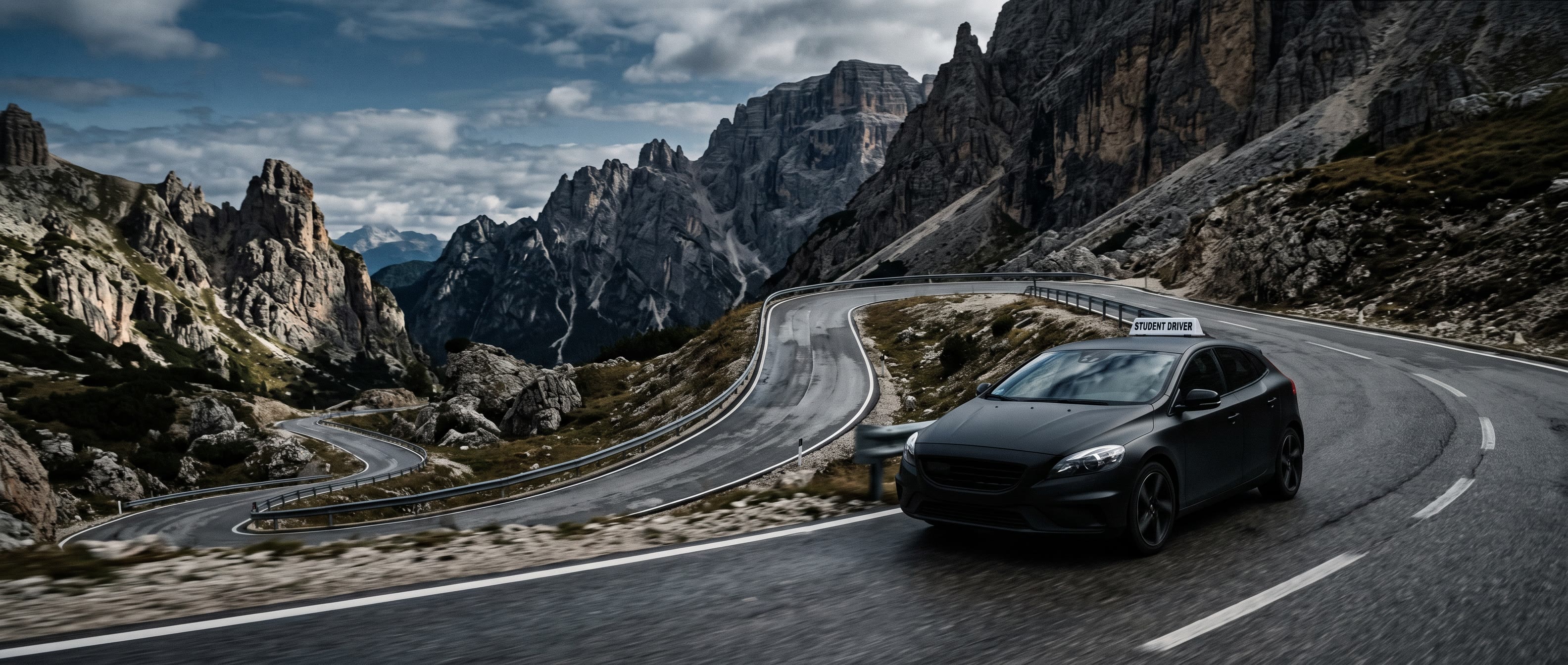 A student-driver car on a winding road through rocky mountains